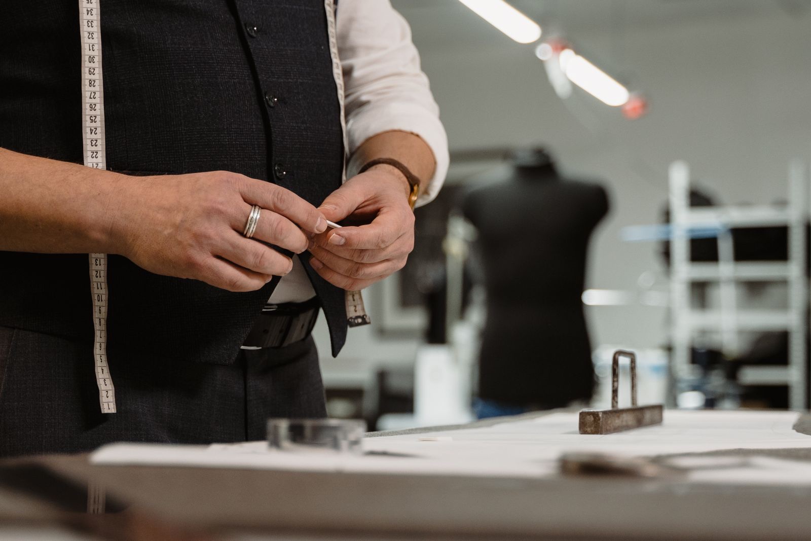 A tailor’s hands fitting a garment on a mannequin in the atelier
