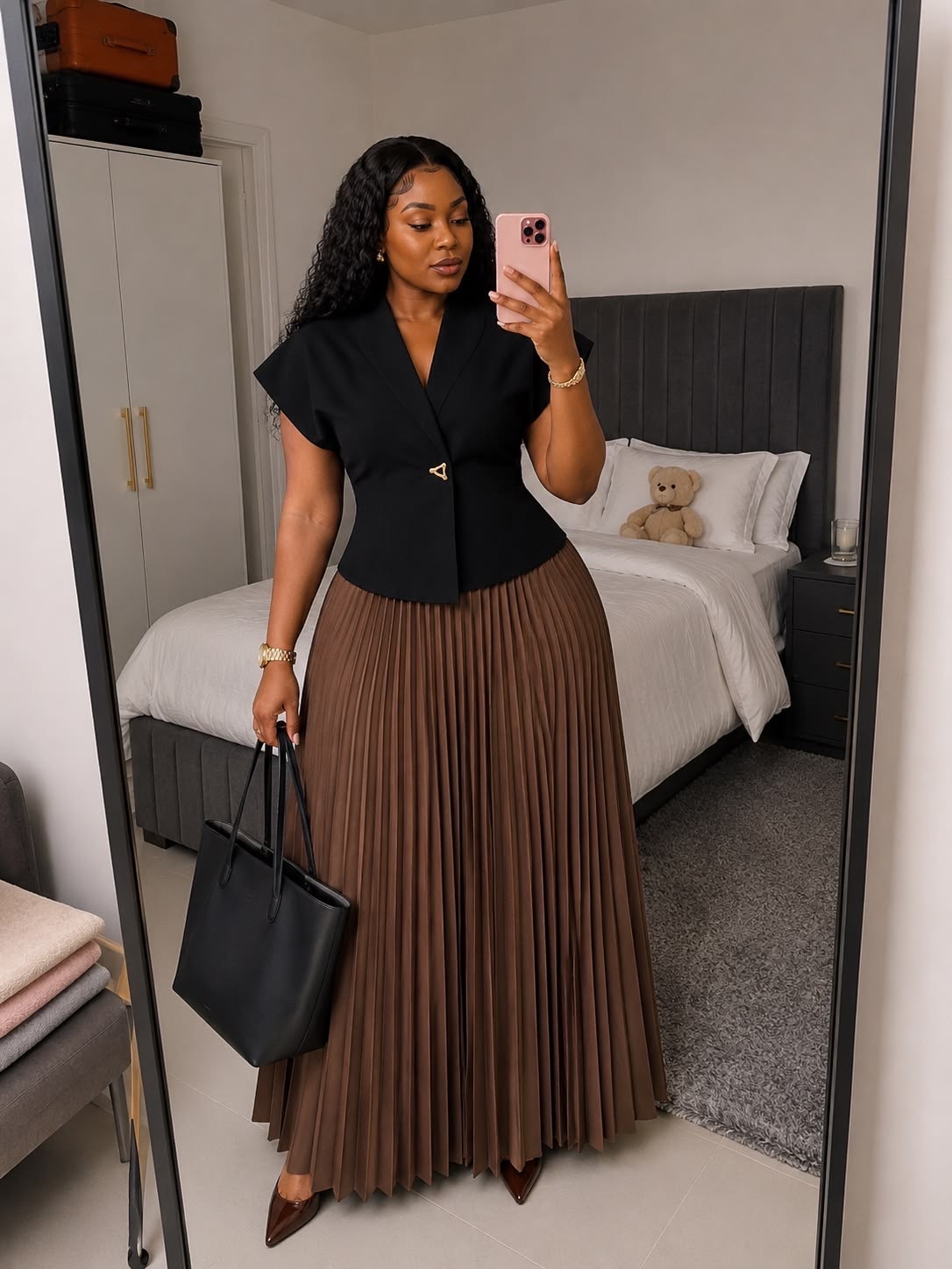 Fitted black blazer worn with a camel pleated skirt
